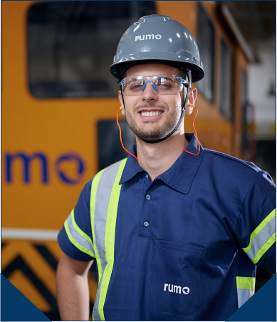 Homem com uniforme da Rumo e equipamentos de segurança. Ao fundo um vagão da Rumo